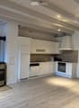 kitchen with white cabinets, wooden floor, fireplace, modern appliances