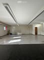 Empty room with white walls, concrete floor, fluorescent lighting, and a few windows. No furniture or equipment present.