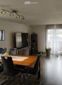 Modern dining area with a wooden dining table, six chairs, a television, a cabinet, and a potted plant near the sliding glass doors.