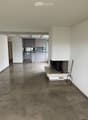Empty living space with a fireplace, modern kitchen in the background, polished tile floor, and white walls.