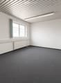 Empty room with white walls, grey carpet, a window with a green curtain, and a radiator below the window.