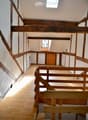 Exposed wooden beams, white walls, wooden staircase, wooden floor, small window
