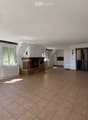 Bright hallway with tiled floor, large windows, fireplace, and open doorway leading to another room.