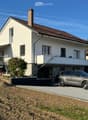 Two-story house with white exterior, brown roof, garage, and parking area.