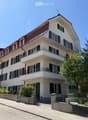 3 story white house, green shutters, balconies, red roof, garden, street view