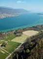 Aerial view of a rural area with fields, a small farm, and a large body of water in the background.