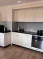 Modern kitchen with white cabinets, black countertops, and stainless steel appliances, including a coffee maker, oven, and sink.