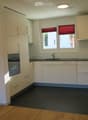 Modern kitchen with white cabinets, black countertops, and a dark tiled floor. Features a sink with a faucet and an oven built into the cabinetry.