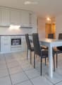 A modern, well-lit kitchen and dining area with white cabinets, a stove, refrigerator, and a dining table with chairs.