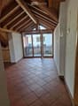 Spacious hallway with exposed wooden beams, terracotta tiled floor, and large sliding glass doors leading to a balcony.