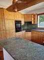 Wooden kitchen with granite countertop, built-in oven, and wooden cabinets.