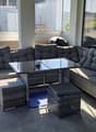 Balcony with wicker seating, glass coffee table, and outdoor view.