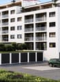 Modern multi-story residential building with balconies, garage, and parking area.