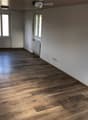 empty room with white walls, wooden floors, two windows, radiator