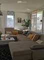 Modern living room with a large sectional sofa, coffee table, side table, pendant light, wall art, and plants.