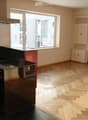 Black and red cabinets, stainless steel appliances, black granite countertops, herringbone wood floors, large window, radiator