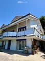 Two-story house with white exterior, blue shutters, balcony with metal railing, and outdoor patio area with a table and chairs.