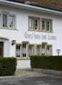 White building with multiple windows, decorative stone trim, and a sign reading "Gasthaus zum Lamm".