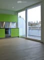 Lime green cupboards, glass door to the balcony, stainless steel oven, wooden floor