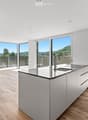 Modern kitchen with light-colored cabinets, a central island, and large windows offering a scenic view of the landscape.