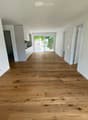 Empty room with light wooden flooring, white walls, and a sliding glass door leading to a balcony.
