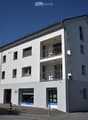 3 story building, white exterior, multiple balconies, garage, windows, door