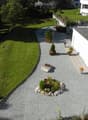 Aerial view of a modern house with a well-maintained garden, gravel driveway, and landscaped greenery.