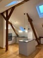 Bright, open-plan attic kitchen with exposed wooden beams, skylights, and modern appliances.