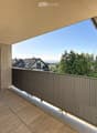 Balcony with wooden flooring, metal railing, and a view of the surrounding landscape and houses.