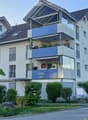 Modern two-story house with multiple balconies, large windows, and a well-maintained garden.