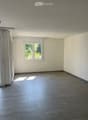 Empty room with light grey tiled floor, white walls, and a window with white frame. Sunlight streams in from the window, casting shadows on the floor.