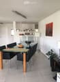 Modern dining area with a glass dining table, black chairs, a floor lamp, a cabinet, and artwork on the wall.