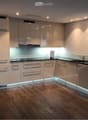 modern kitchen, stainless steel appliances, LED lighting, wooden floors, white cabinets, marble countertop