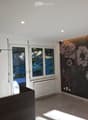 Empty room with white walls, large windows, radiator, and a floral wallpaper mural on one wall.