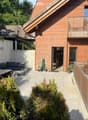 Outdoor patio area with a wooden table, sofa, chairs, and a small balcony with additional seating.