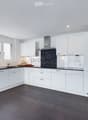 Modern kitchen with white cabinets, dark countertops, and stainless steel appliances. Features a sink, faucet, oven, and range hood.