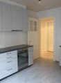 Modern kitchen with white cabinets, black granite countertops, stainless steel sink and oven, and a doorway leading to another room.