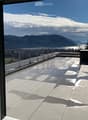 Modern balcony with large glass doors, tiled floor, metal railing, and scenic mountain and lake view.