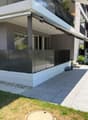 Modern two-story building with a covered balcony area, large windows, and a small garden space.