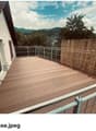 Wooden deck terrace with metal railing, bamboo screen, and scenic mountain view.