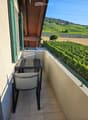 Balcony with a view of vineyards and hills, featuring a table and a chair.