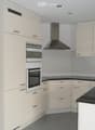 Modern kitchen with light-colored cabinets, stainless steel appliances, black countertops, and a built-in oven.