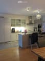 Modern kitchen with white cabinets, stainless steel appliances, island, and dining area with wooden table and chairs.