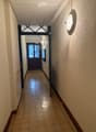Hallway with beige tiled floor, light-colored walls, and a decorative door at the end.