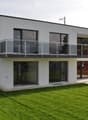 modern white house, glass windows, glass balcony, red door, large green lawn