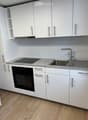 modern kitchen with white cabinetry, granite countertops, stainless steel sink and faucet, induction cooktop, built-in oven, dishwasher and washing machine visible