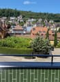 Balcony overlooking a town with houses, trees, and a clear blue sky.
