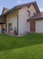 Two-story house with beige walls, red-tiled roof, and a covered patio area with outdoor furniture.