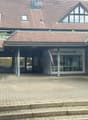 Two-story building with a tiled roof, a covered entrance area, and signage reading "Foto Fachgeschäft" (photo shop).