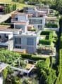 Aerial view of a residential neighborhood with multiple modern houses, well-maintained gardens, and solar panels on one roof.